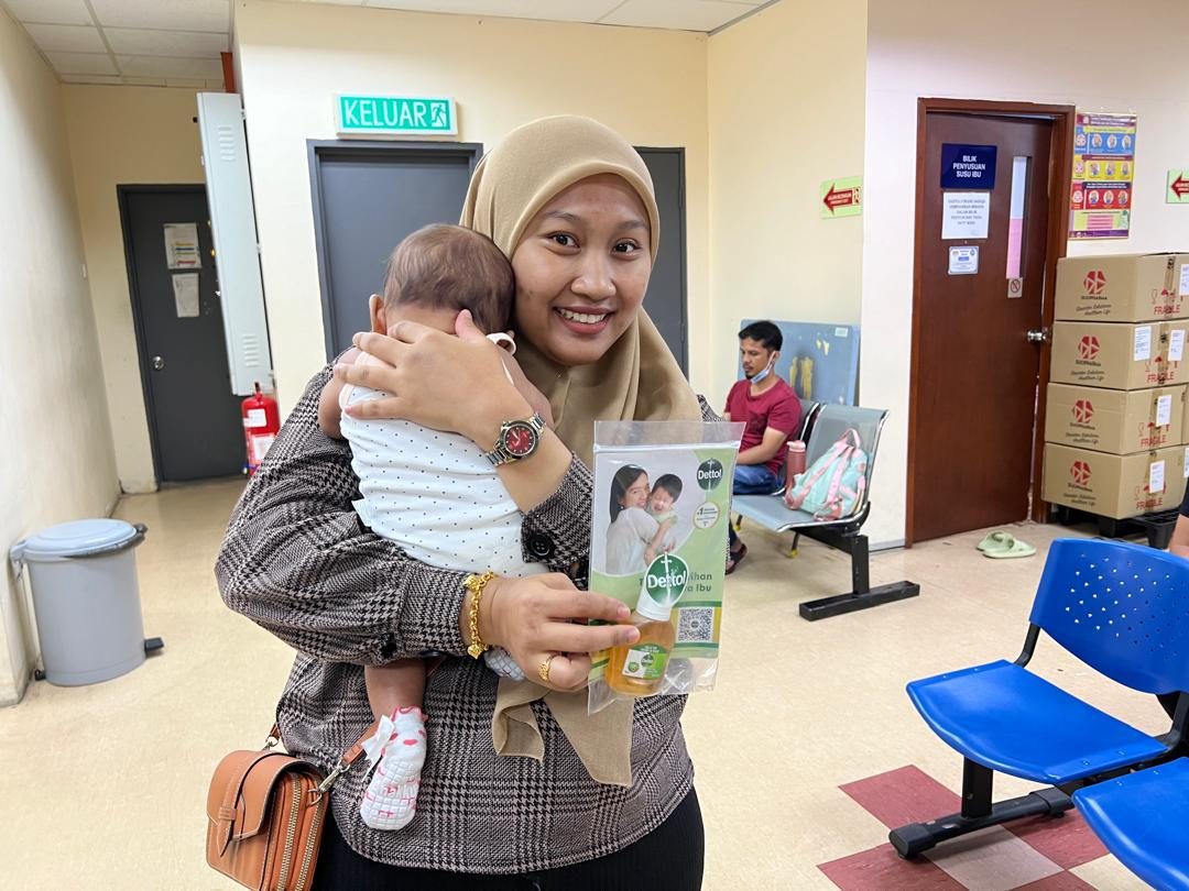 A mother carries her baby and a Nurture Circle sample pack at a government hospital