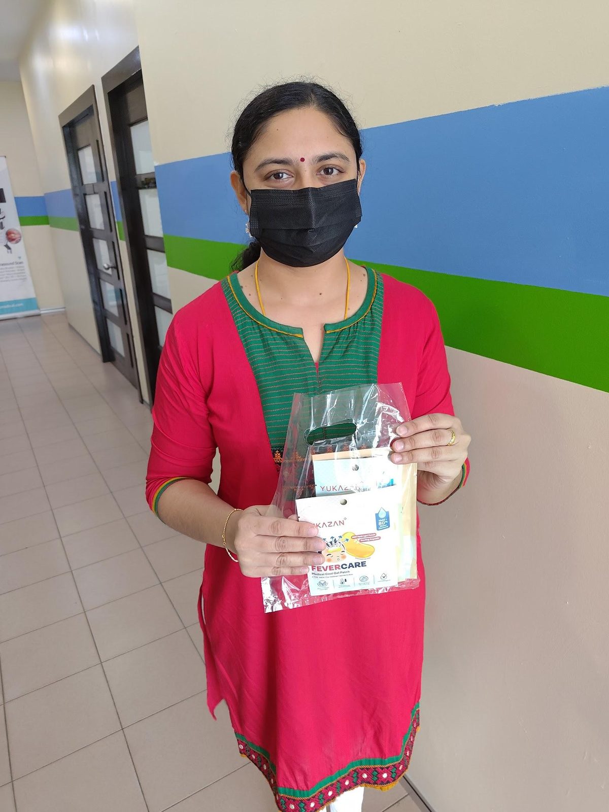A participant holds a Nurture Circle sample pack in a Malaysian clinic corridor