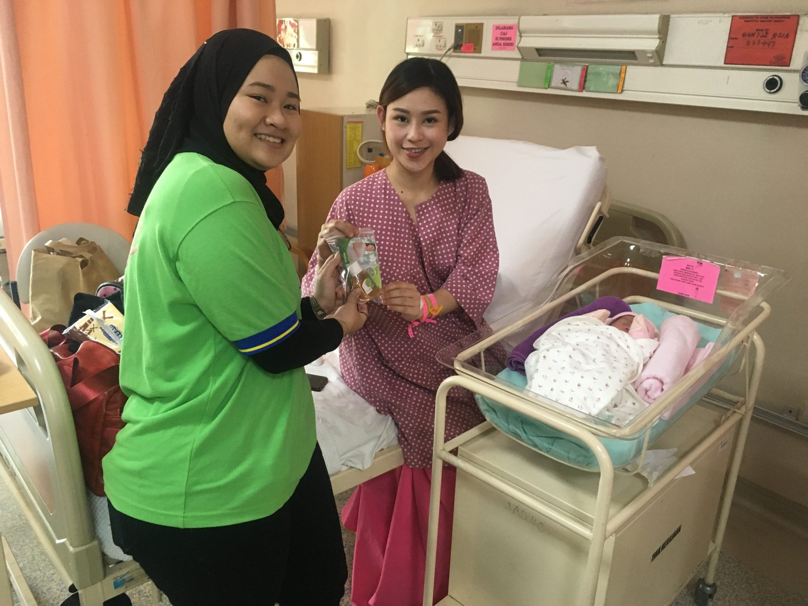 An Avante facilitator meets a new mother beside a bassinet in a postnatal ward