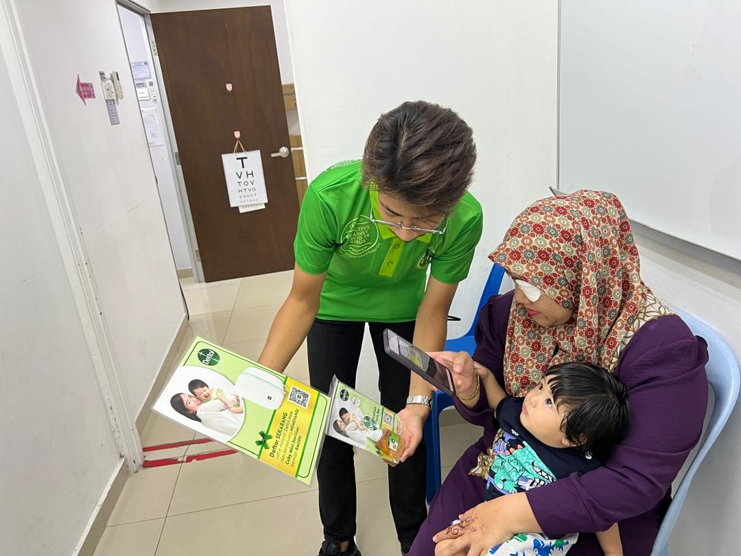 An Avante programme facilitator hands educational materials to a mother and child at a clinic